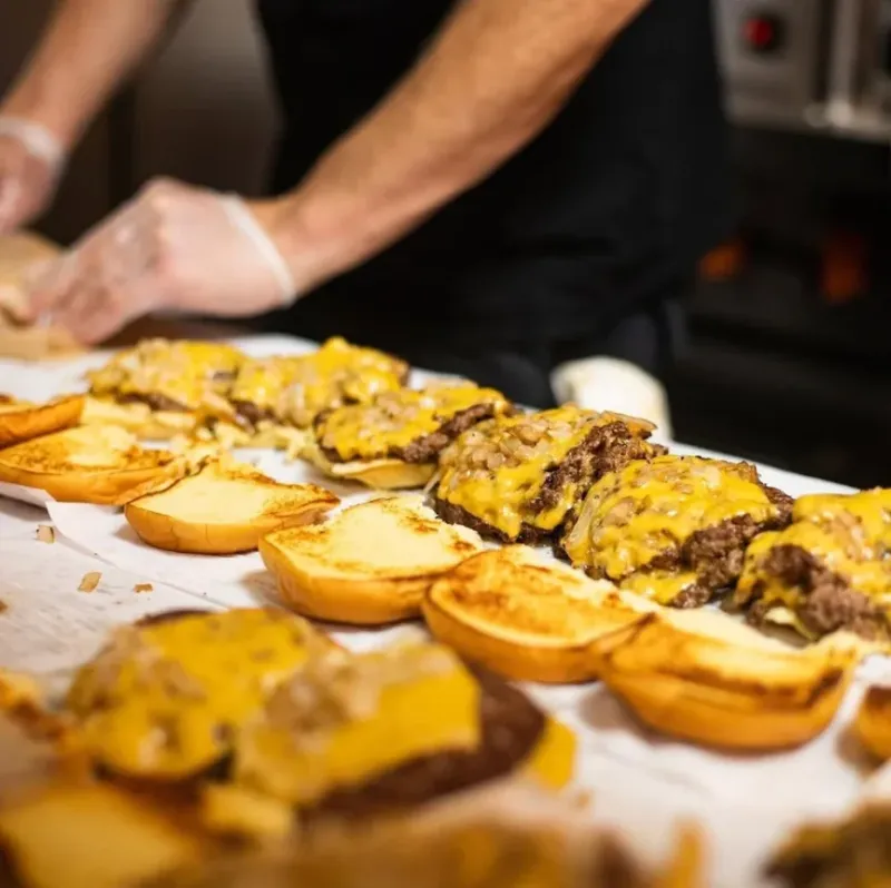 7th Street Burger team preparing fresh cheeseburgers on the assembly line